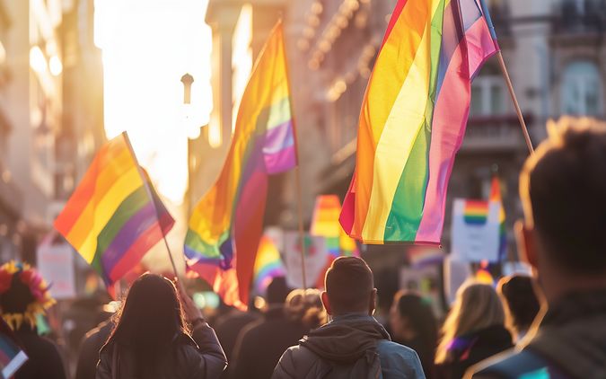 Viele Menschen mit bunten Regenbogen-Fahnen sind auf der Straße unterwegs.